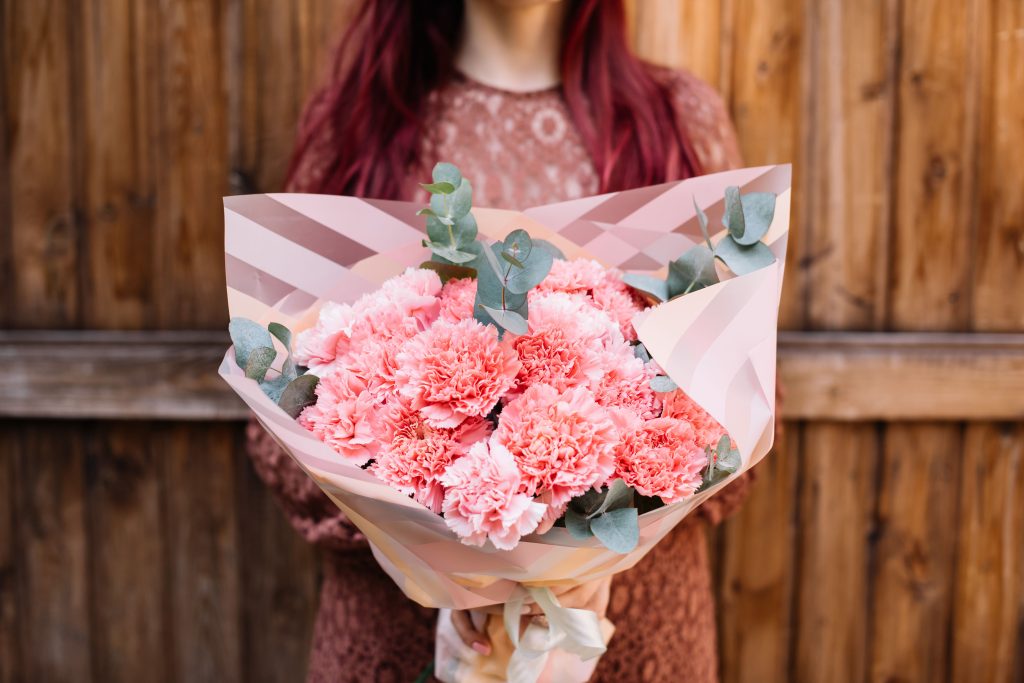 Person holding a bouquet of pink carnations