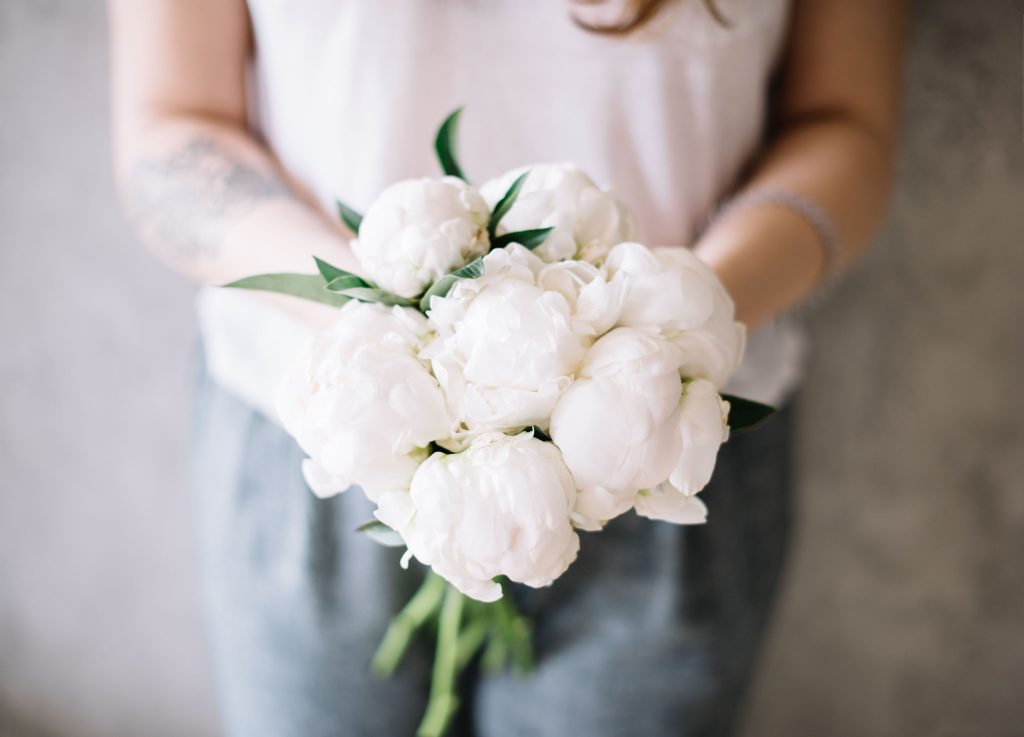 Person holding a bouquet of peonies